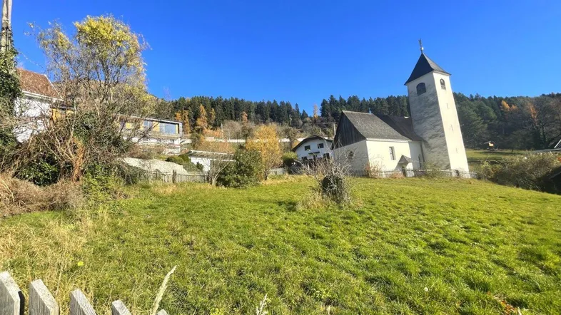 Blick auf eine Kirche und die umliegende grüne Landschaft unter strahlend blauem Himmel.