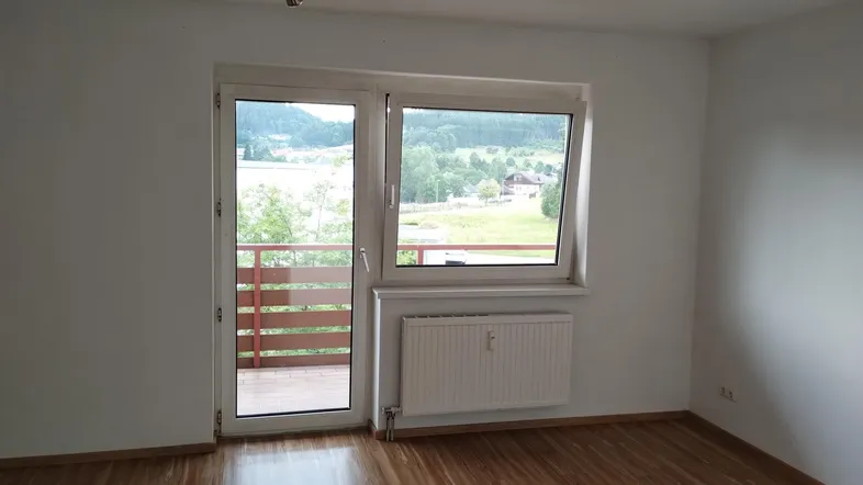 Helles Zimmer mit Laminatboden und Zugang zum Balkon, bietet einen schönen Blick ins Grüne.