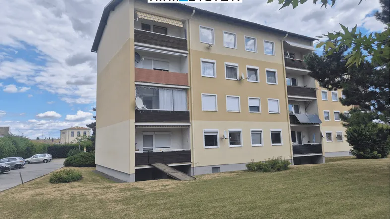 Außenansicht eines Mehrfamilienhauses mit Balkonen und einer Zugangsrampe.