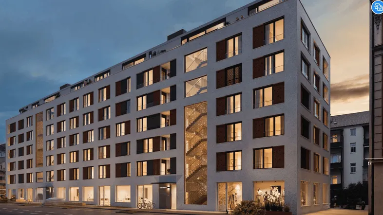 Moderne Wohnanlage mit großen Fenstern und Balkonen, beleuchtet in der Abenddämmerung.