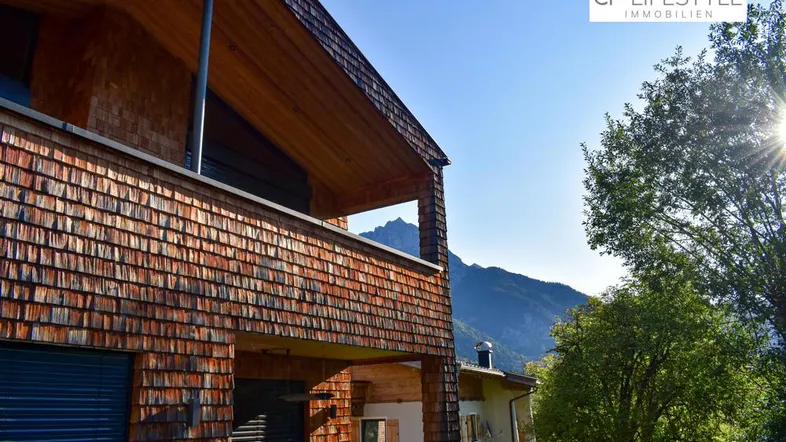 Modernes Gebäude mit Holzfassade und Bergblick unter blauem Himmel.