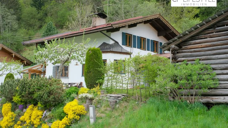 Traditionelles Haus im alpinen Stil mit gepflegtem Garten und grüner Umgebung.
