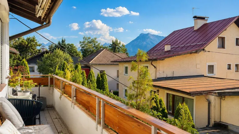 Sonniger Balkon mit Holzelementen und herrlichem Blick auf die umliegende Berglandschaft.