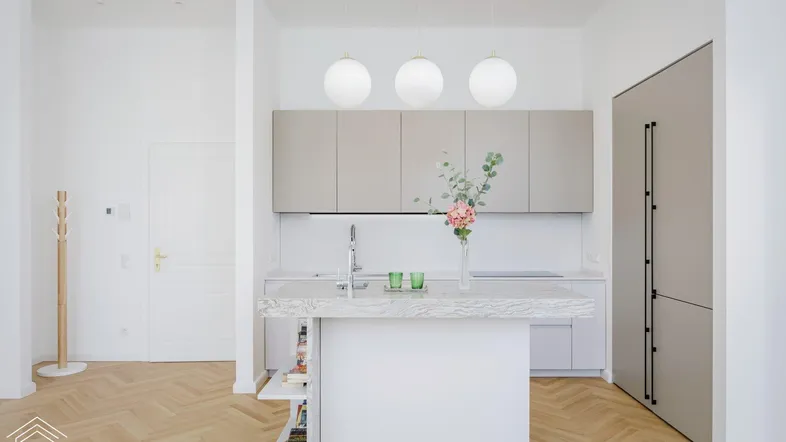 Moderne Küche mit Kücheninsel, hellen Schränken und Fischgrätparkettboden.