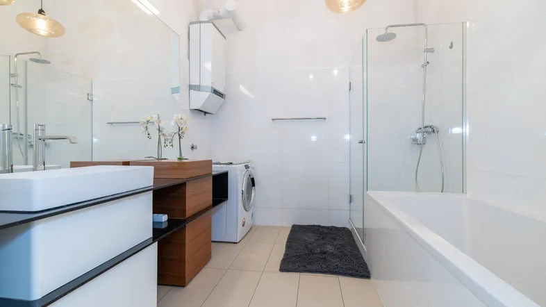 Modernes Badezimmer mit Badewanne, Dusche, Waschmaschine und großem Spiegel.