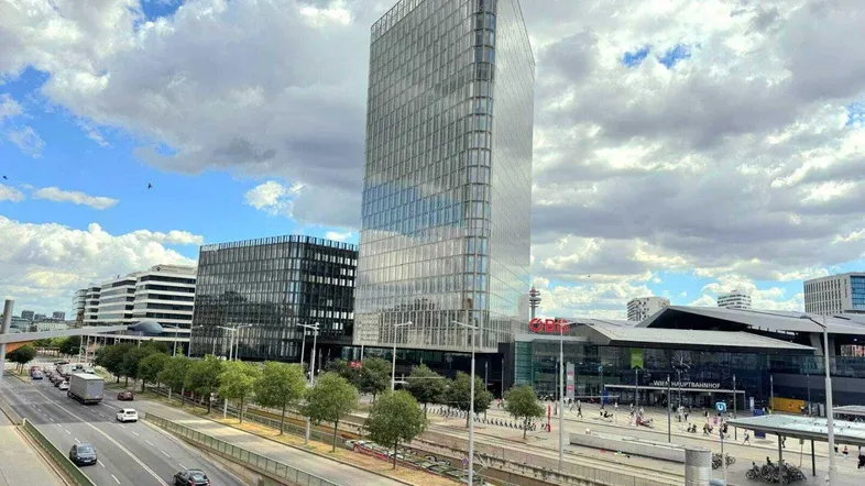 Beeindruckender Blick auf ein modernes Hochhaus mit Glasfassade und den Wiener Hauptbahnhof.