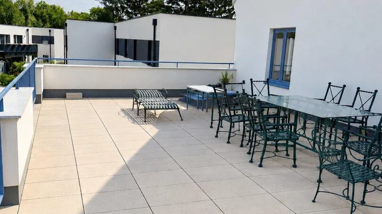 Geräumige und sonnige Dachterrasse mit Fliesenboden und Gartenmöbeln, ideal für entspannte Stunden im Freien.