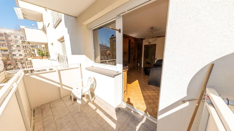 Heller Balkon mit Fliesenboden und Blick in den Wohnbereich, ideal für sonnige Stunden.