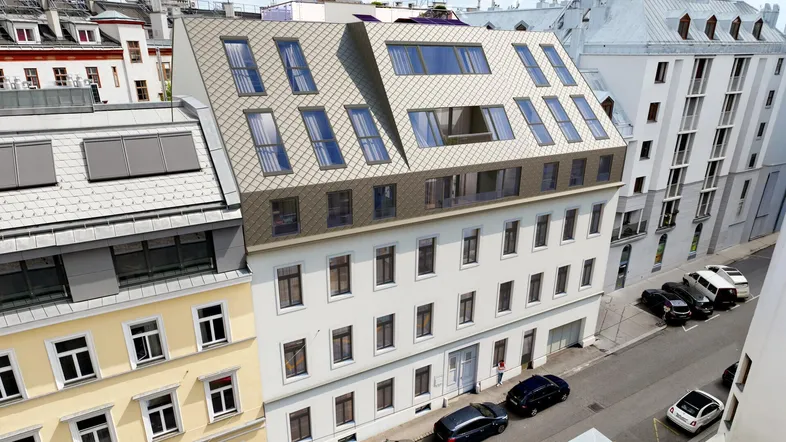 Luftaufnahme eines Gebäudes mit neuem Dachausbau und modernen Dachfenstern in städtischer Umgebung.