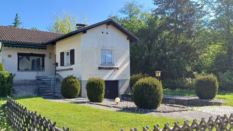 Einfamilienhaus mit gepflegtem Vorgarten, Rasenfläche und Kiesweg unter blauem Himmel.