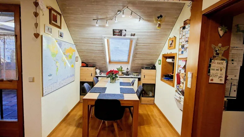 Gemütlicher Essbereich im Dachgeschoss mit Holztisch, Dachfenster und schräger Holzdecke.