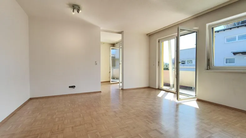 Helles Wohnzimmer mit Parkettboden und Zugang zum sonnigen Balkon, ideal für entspannte Stunden.