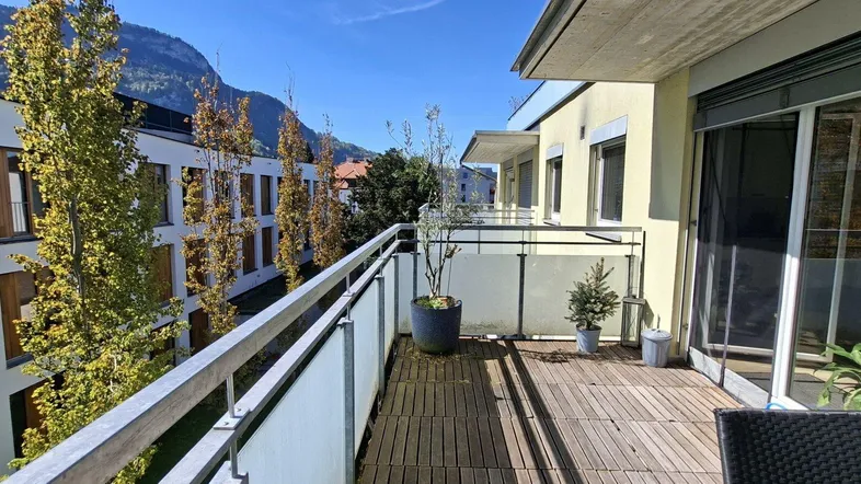 Geräumiger Balkon mit Holzboden, Pflanzen und einem schönen Blick auf die umliegenden Berge.