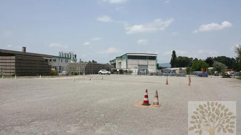 Großes Freigelände mit Industriebauten und Schotterfläche unter blauem Himmel, ideal für gewerbliche Nutzung.