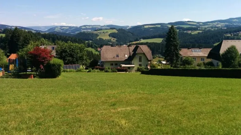 Haus mit großem Rasen und weitem Blick auf die umliegende Hügellandschaft unter blauem Himmel.