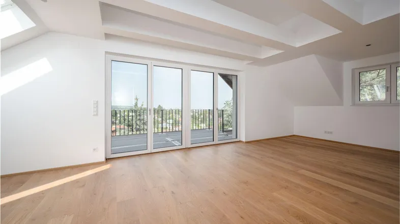 Helles, geräumiges Zimmer mit Holzboden, Dachschrägen und Zugang zu einem Balkon mit Weitblick.