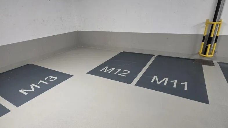 Leere Parkplätze M11, M12 und M13 in einer modernen Tiefgarage mit sauberem Boden.
