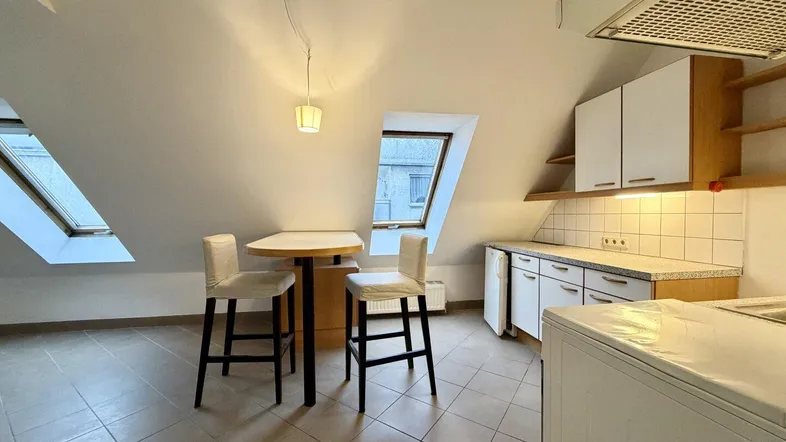 Helle Dachgeschosswohnung mit kleiner Küche, Bar und Dachfenstern, ideal für Singles.