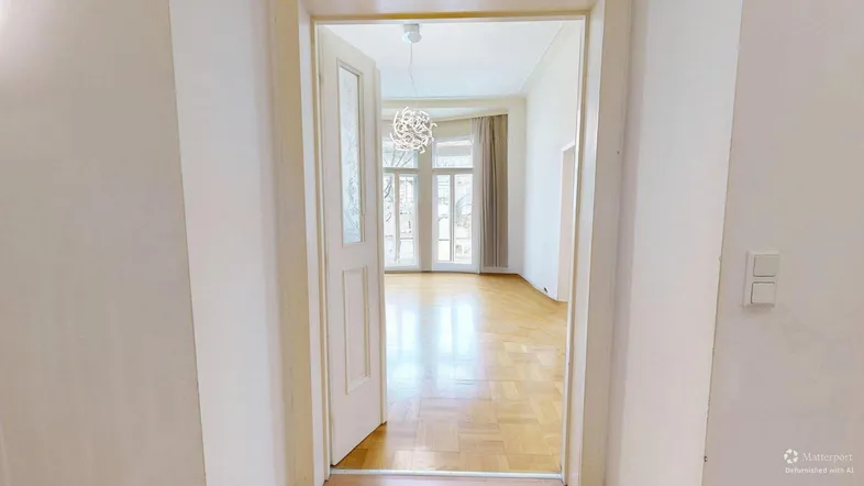 Helles Wohnzimmer mit Parkettboden und großen Fenstern, das viel Tageslicht hereinlässt.