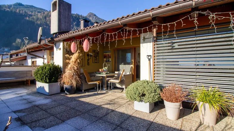 Geräumige Sonnenterrasse mit Sitzgelegenheiten, Pflanzen und Blick auf die umliegende Berglandschaft.