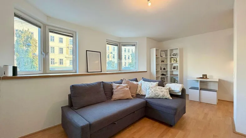 Helles Wohnzimmer mit Ecksofa, Holzfußboden und Blick auf die Stadt.