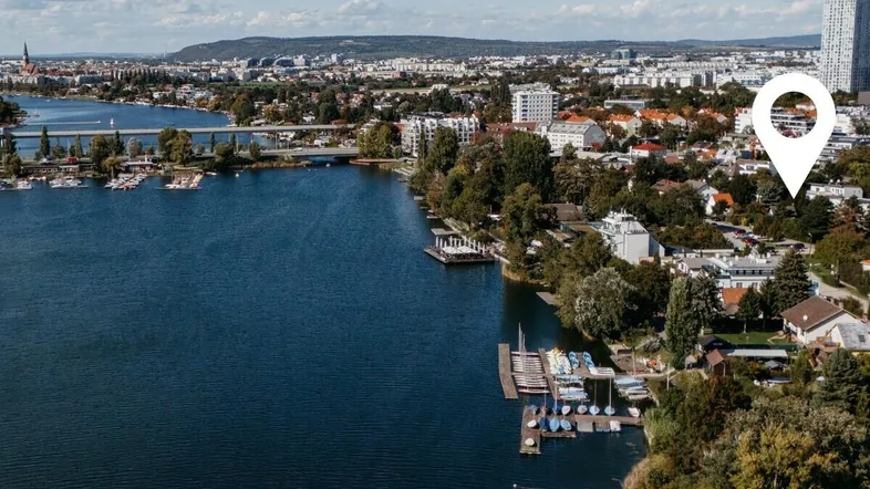 Luftaufnahme einer Stadtlandschaft mit See und umliegenden Gebäuden unter blauem Himmel.