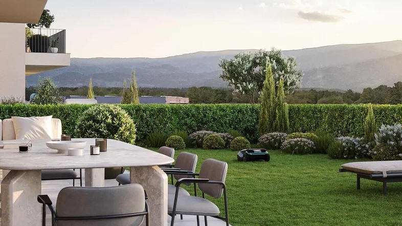 Moderne Terrasse mit Essbereich, umgeben von einem gepflegten Garten und Bergblick.