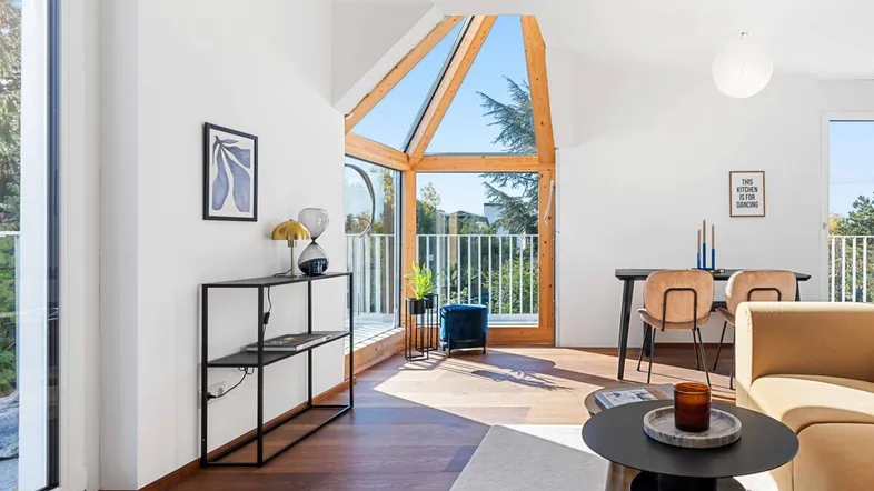 Heller Wohn- und Essbereich mit großen Fenstern, Holzboden und modernem Design.