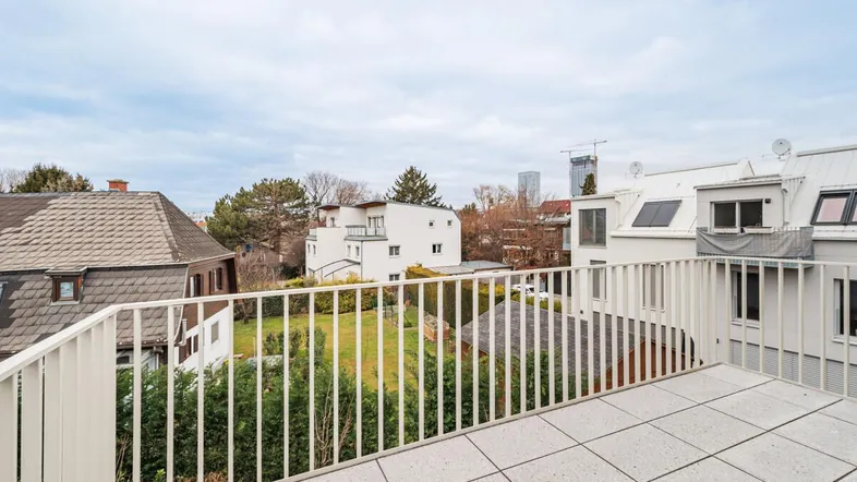 Geräumige Dachterrasse mit Fliesenboden und Blick auf die umliegenden Gebäude.