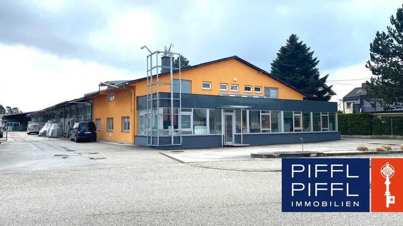 Außenansicht eines modernen Gewerbegebäudes mit orangefarbener Fassade, großen Fenstern und Parkplätzen.