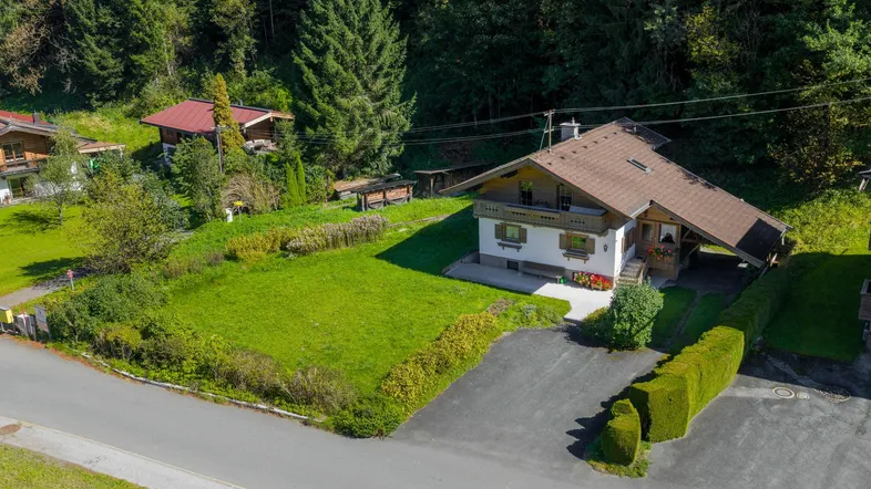Luftaufnahme eines charmanten Hauses mit großem Garten, umgeben von grünen Wäldern und Natur.