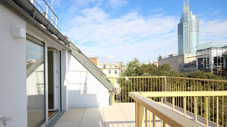 Geräumige Dachterrasse mit Fliesenboden und weitem Blick über die Stadt und moderne Architektur.