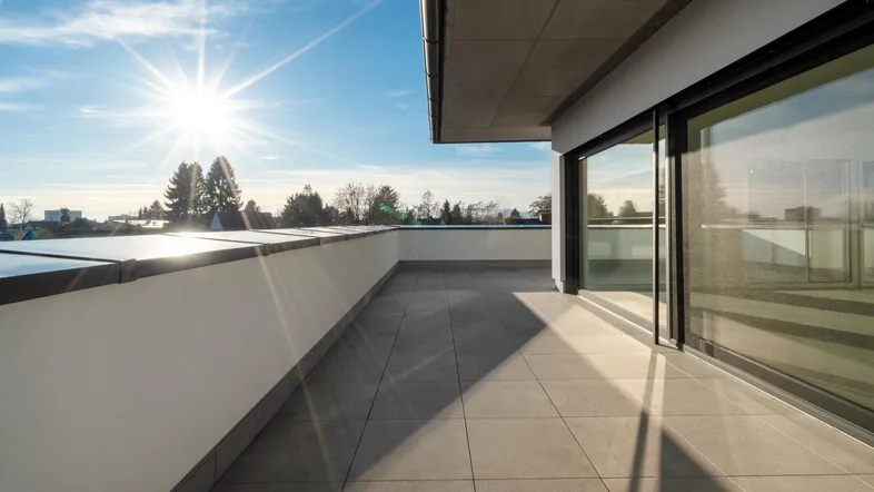 Große, sonnige Dachterrasse mit modernen Fliesen und weitem Blick über die Umgebung.