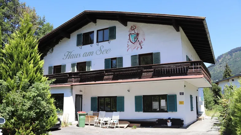 Traditionelles Haus im alpinen Stil mit Balkon, grünen Fensterläden und Bergblick.