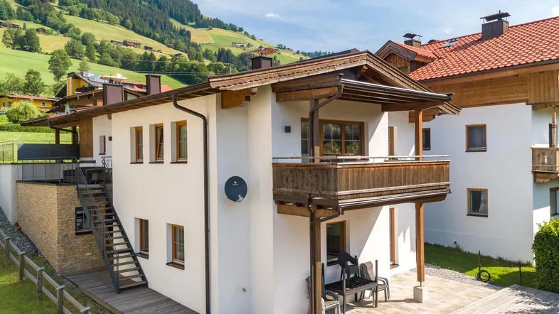 Modernes Wohnhaus mit Balkon und Terrasse in alpiner Umgebung und Bergblick.