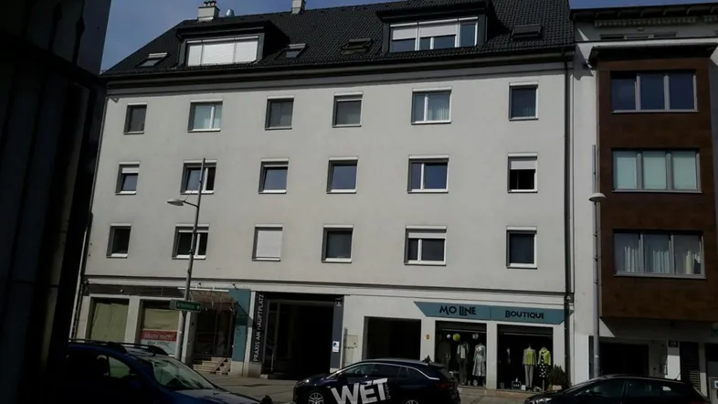 Ansicht der modernen Fassade eines Mehrfamilienhauses mit zahlreichen Fenstern und Dachgauben.