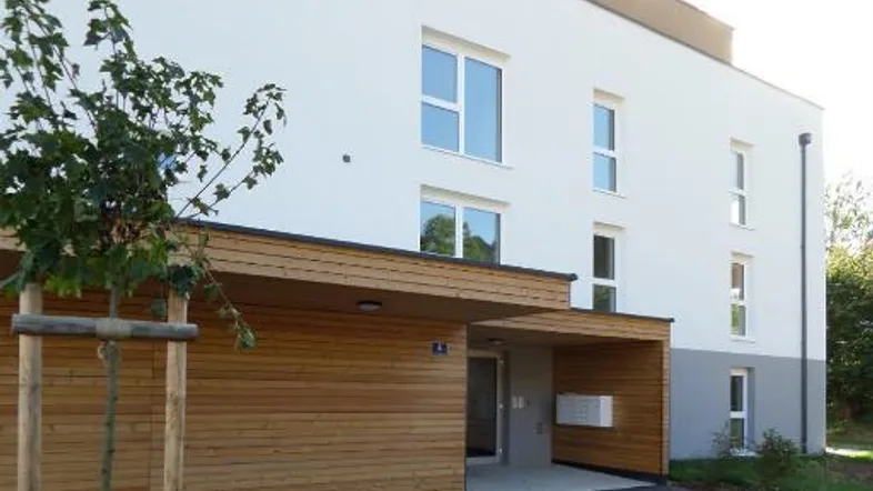 Moderne Gebäudefassade mit Holzelementen und Eingangsbereich in einem Neubau.