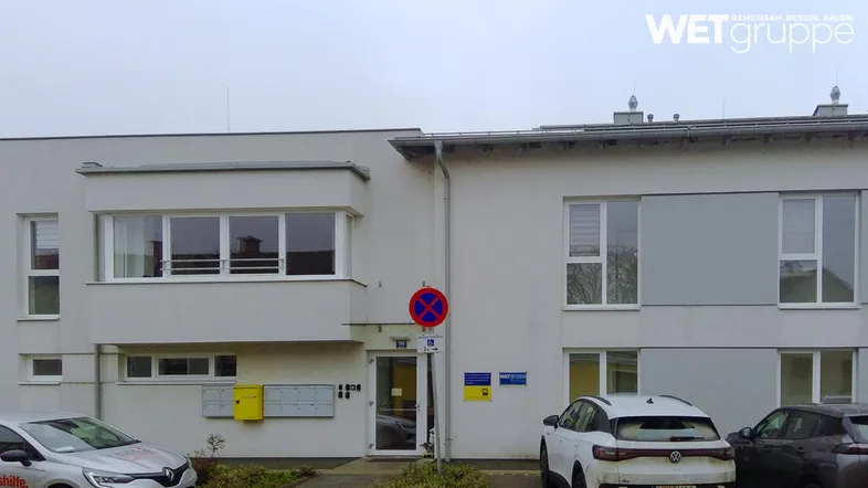 Moderne Fassade eines Wohngebäudes mit großen Fenstern und Eingangsbereich.