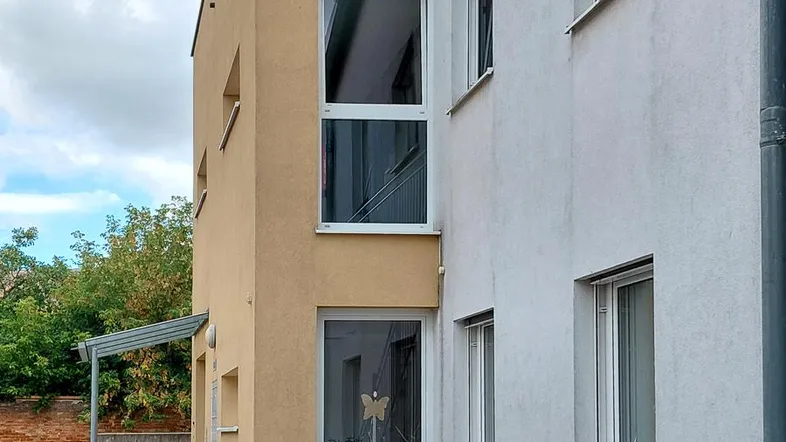 Seitenansicht eines modernen Wohngebäudes mit hellen Fassaden und vertikalen Fenstern.
