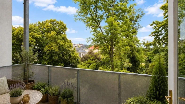 Heller Balkon mit Pflanzen und einem weiten Blick ins Grüne und auf die Stadt.