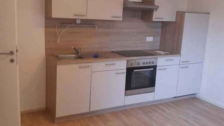 Moderne Einbauküche mit hellen Holz- und weißen Fronten, ausgestattet mit Backofen und Kochfeld.