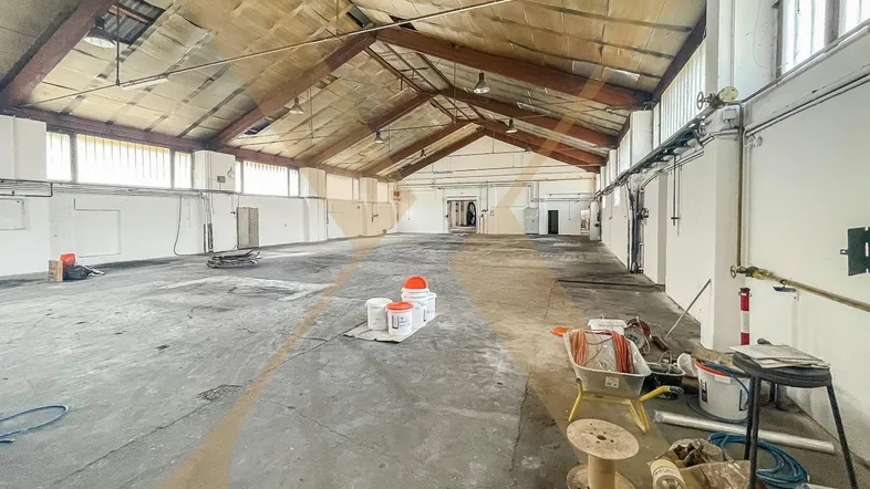 Große, leere Lagerhalle mit hoher Decke und sichtbaren Dachbalken, bereit für die Nutzung.
