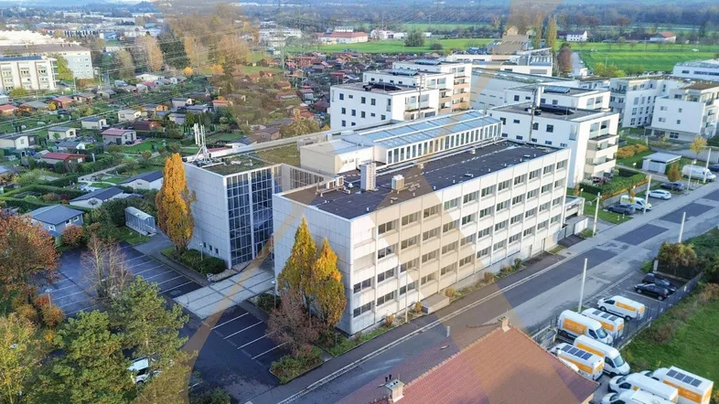 Luftaufnahme des Gebäudekomplexes mit umliegenden Wohngebäuden und viel Grünfläche.