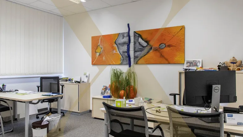 Helles Büro mit mehreren Arbeitsplätzen, modernen Kunstwerken und funktionaler Einrichtung.