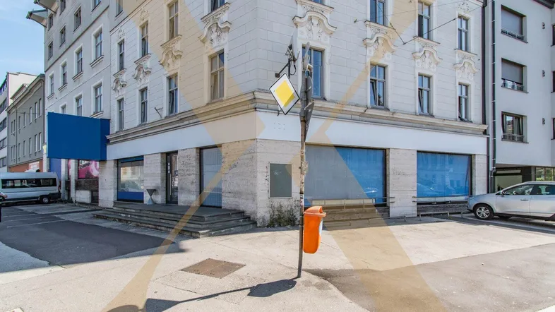 Gebäudeansicht an einer Straßenecke mit Ladenflächen im Erdgeschoss und klassischer Fassade.
