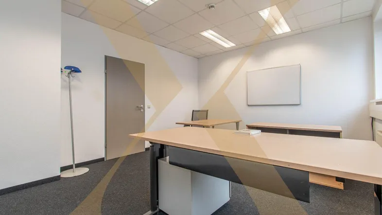 Helles Büro mit Teppichboden, mehreren Schreibtischen und einer Tür, ideal für geschäftliche Nutzung.