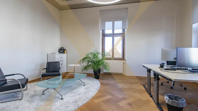Geräumiges Büro mit Fischgrätparkett, hohen Decken und moderner Beleuchtung, ideal für produktives Arbeiten.