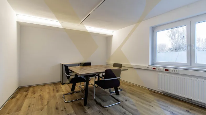 Modernes Büro mit Holzboden, großem Fenster und einem Besprechungstisch für vier Personen.
