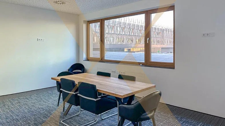 Moderner Konferenzraum mit Holztisch, bequemen Stühlen und Blick auf die Umgebung.