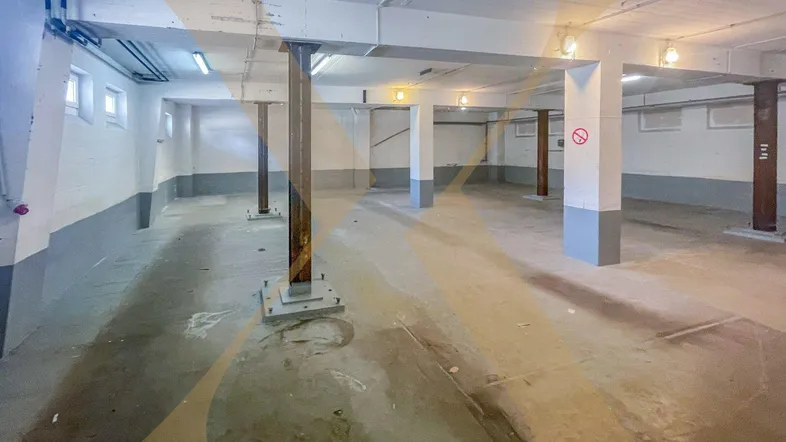 Großer, offener Kellerraum mit tragenden Säulen und Betonboden, ideal als Lagerfläche.